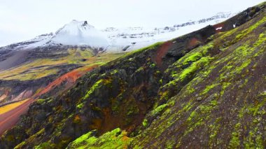 Sersemletici yeşil tepeler ve görkemli, karla kaplı zirveler sakin, resimli dağ manzarası.