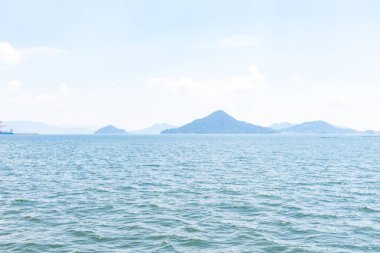 Bu Hiroşima Körfezi 'nin bir görüntüsü. Dalgalar, tuzlu suyun dalgalı tepelere ulaşmasıyla güzel ve sakin görünüyor. Güzel mavi Japon gökyüzünün içinde beyaz bulutlar var..