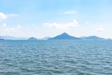 Bu Hiroşima Körfezi 'nin bir görüntüsü. Dalgalar, tuzlu suyun dalgalı tepelere ulaşmasıyla güzel ve sakin görünüyor. Güzel mavi Japon gökyüzünün içinde beyaz bulutlar var..