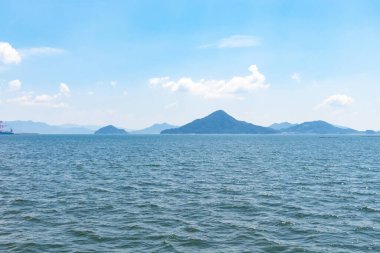 Bu Hiroşima Körfezi 'nin bir görüntüsü. Dalgalar, tuzlu suyun dalgalı tepelere ulaşmasıyla güzel ve sakin görünüyor. Güzel mavi Japon gökyüzünün içinde beyaz bulutlar var..