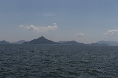 Bu Hiroşima Körfezi 'nin bir görüntüsü. Dalgalar, tuzlu suyun dalgalı tepelere ulaşmasıyla güzel ve sakin görünüyor. Güzel mavi Japon gökyüzünün içinde beyaz bulutlar var..