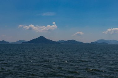 Bu Hiroşima Körfezi 'nin bir görüntüsü. Dalgalar, tuzlu suyun dalgalı tepelere ulaşmasıyla güzel ve sakin görünüyor. Güzel mavi Japon gökyüzünün içinde beyaz bulutlar var..