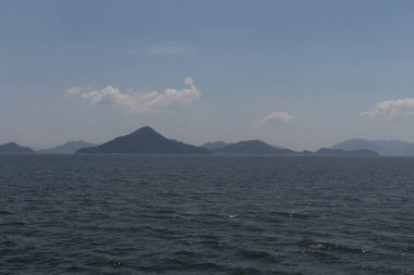 Bu Hiroşima Körfezi 'nin bir görüntüsü. Dalgalar, tuzlu suyun dalgalı tepelere ulaşmasıyla güzel ve sakin görünüyor. Güzel mavi Japon gökyüzünün içinde beyaz bulutlar var..