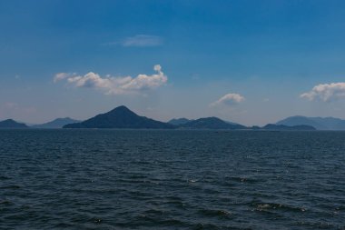 Bu Hiroşima Körfezi 'nin bir görüntüsü. Dalgalar, tuzlu suyun dalgalı tepelere ulaşmasıyla güzel ve sakin görünüyor. Güzel mavi Japon gökyüzünün içinde beyaz bulutlar var..