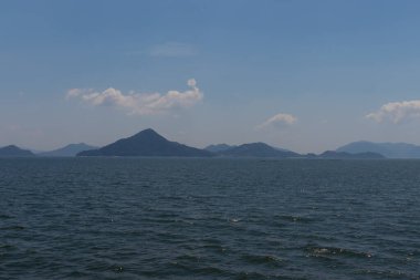 Bu Hiroşima Körfezi 'nin bir görüntüsü. Dalgalar, tuzlu suyun dalgalı tepelere ulaşmasıyla güzel ve sakin görünüyor. Güzel mavi Japon gökyüzünün içinde beyaz bulutlar var..