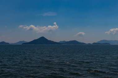 Bu Hiroşima Körfezi 'nin bir görüntüsü. Dalgalar, tuzlu suyun dalgalı tepelere ulaşmasıyla güzel ve sakin görünüyor. Güzel mavi Japon gökyüzünün içinde beyaz bulutlar var..