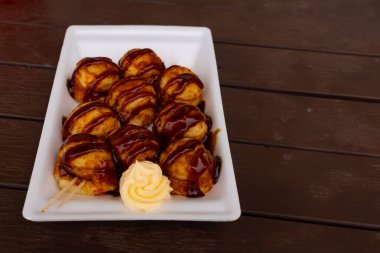 Tatlı ve lezzetli soslu bu altın kahverengi toplar Takoyaki 'dir. Onlar Japonya 'nın temel taşlarıdır. Burada beyaz bir tabakta servis edilirken ve yanında mayonez parçacıkları ile görülürler..
