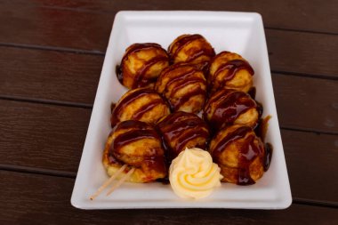 Tatlı ve lezzetli soslu bu altın kahverengi toplar Takoyaki 'dir. Onlar Japonya 'nın temel taşlarıdır. Burada beyaz bir tabakta servis edilirken ve yanında mayonez parçacıkları ile görülürler..