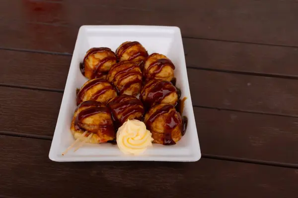Tatlı ve lezzetli soslu bu altın kahverengi toplar Takoyaki 'dir. Onlar Japonya 'nın temel taşlarıdır. Burada beyaz bir tabakta servis edilirken ve yanında mayonez parçacıkları ile görülürler..