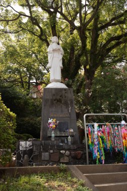 Bu, Japonya 'daki Nagasaki Barış Parkı' nda sergilenen birçok heykelden biridir. Küçük bir kızın beyaz heykeli. Üzerinde Japonca yazılar olan gri kaideyi. Düşenler için üste çiçekler ve su şişeleri görülebilir..