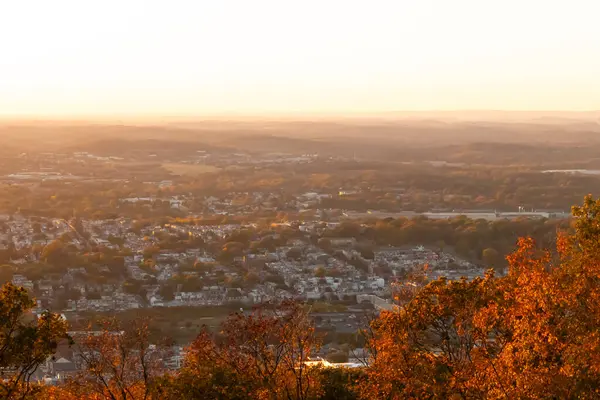 Evleri ve caddeleri olan bir vadinin çok güzel bir görüntüsü. Güneşin tüm nesneleri öptüğü son anın altın parıltısı. Güneş gün batıyor..