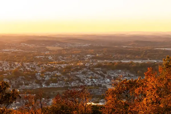 Evleri ve caddeleri olan bir vadinin çok güzel bir görüntüsü. Güneşin tüm nesneleri öptüğü son anın altın parıltısı. Güneş gün batıyor..