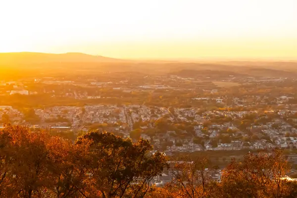 Evleri ve caddeleri olan bir vadinin çok güzel bir görüntüsü. Güneşin tüm nesneleri öptüğü son anın altın parıltısı. Güneş gün batıyor..