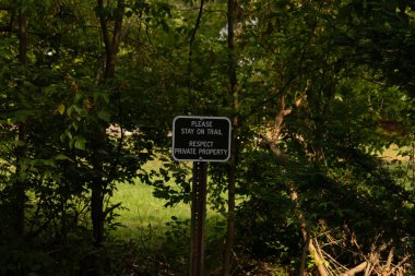 Lütfen kaşifin yürümesi için patikayı işaretleyen yol işaretini takip edin. Beyaz kenarlı kahverengi tabela kimsenin özel mülke girmemesi ya da yaralanmaması için göze çarpıyor. İşaret, insanları tehlikeden uzak tutmak ya da yaralanmaktan korumak için.. 