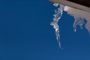Bu buz sarkıtı çatıdan sarkan kadar güzel görünüyor. Donmuş suyun sivri mızrağı ışığı yakalıyor ve neredeyse parıldıyor. Arkadaki mavi gökyüzü bu görüntüyü oluşturmaya yardımcı olur..
