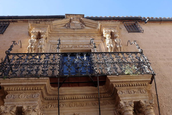 Fragment of old house, with wooden window and small balcony and metal railings. Classical Spanish architecture with white plastered wall, Ronda, Spain. High quality photo