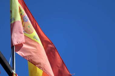 Mavi gökyüzüne karşı büyük siyah bir direkte dalgalanan İspanyol bayrağının ayrıntıları. Yüksek kalite fotoğraf