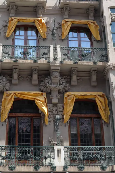 Ahşap pencereli, sarı çerçeveli, küçük balkon ve metal parmaklıklı eski bir ev parçası. Beyaz duvarlı klasik İspanyol mimarisi, Ronda, İspanya. Yüksek kalite fotoğraf