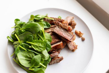 Bir tabak et ve ıspanak. Et küçük parçalara bölünmüş.