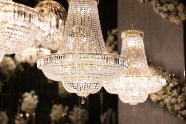 Bir sürü kristalin asılı olduğu bir dizi avize. Avizeler yanıyor ve tavandan sarkıyor.