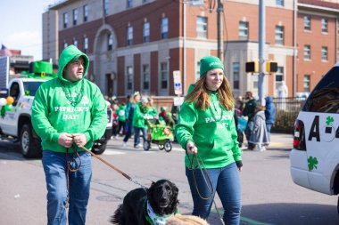 Scranton, Pennsylvania - 8 Mart 2025: St. Patrick Geçit Töreni, Erkek ve bir kadın köpeklerini sokakta gezdiriyorlar. Üzerinde 