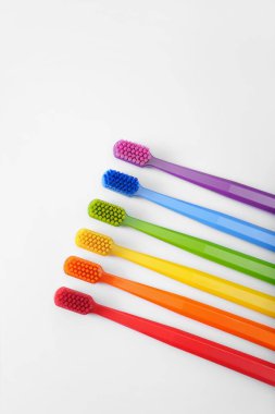 Beyaz arka planda altı renkli diş fırçası. Gökkuşağı. Mesaj için yer. Ayin gibi. Ağız temizliği. Çocukların Yeri.