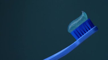 Mavi arka planda diş macunu olan mavi plastik diş fırçası. Işığın etkisi. Ağız boşluğuna dikkat et..