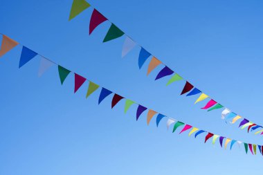 Mavi gökyüzünde uçuşan renkli kiraz kuşlarının fotoğrafı. Bayram bayrakları. Metin için boşluk.