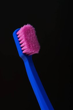 Siyah arka planda pembe tüyleri olan plastik bir diş fırçası kullanılmış. Mikroplar. Çöpe atıp yenisiyle değiştirmenin zamanı geldi..