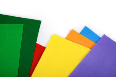 Beyaz arka planda gökkuşağı renklerinde renkli keçeli kumaş örnekleri. El sanatları, DIY, tekstil tasarımı, çocuk sanatı, dikiş projeleri ve renkli ürün sunumları için ideal. Metin için yer.