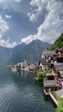 Avusturya Hallstatt 'ün resimli bir görüntüsü. Video geniş bir açıdan çekiliyor. Büyük dağların arasına yerleşmiş sessiz bir göl köyü..