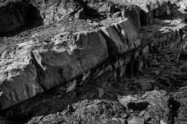 Yaşlı, pejmürde kayalık surat ve büyük çatlaklar ve katmanlarla bölünmüş..