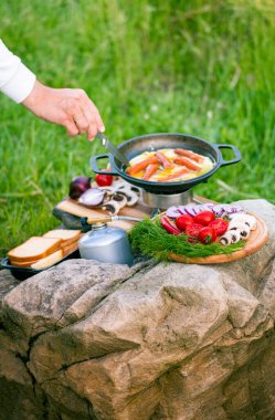 Kızartma tavasında yemek pişirmek, açık havada ateşin yanında..
