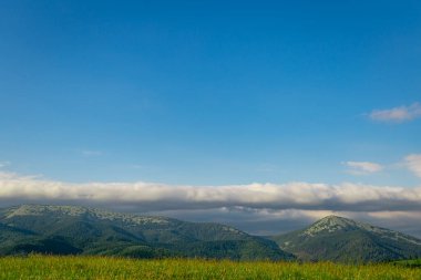 Dağların en güzel manzarası, güneşli bir günde bulutlu gökyüzü..