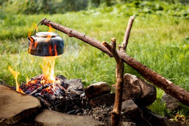 Ormanda açık ateşin üzerinde çay yapmak. Tencere dibin kara seninki benden kara..