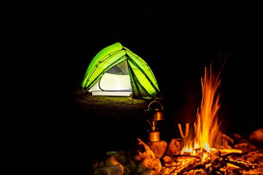 Gece bir çadırla ateşin yanında kamp yapmak..
