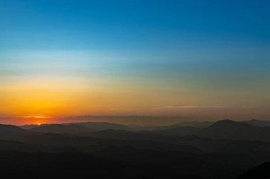 Dağın tepesinde gün batımı, dağ zirveleri dağ manzarasının arka planında.