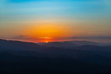 Dağın tepesinde gün batımı, dağ zirveleri dağ manzarasının arka planında.