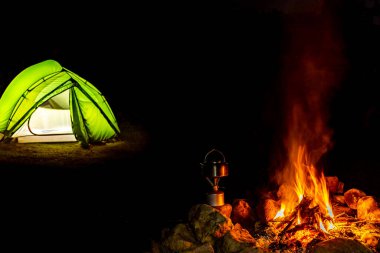 Gece bir çadırla ateşin yanında kamp yapmak..