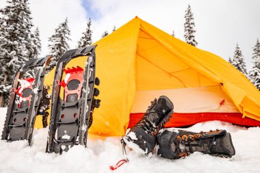 Turuncu çadırda kamp malzemeleriyle kış ormanlarında kamp yapmak..