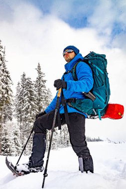 Sırt çantası ve kar ayakkabılarıyla dağlarda kış yürüyüşü..