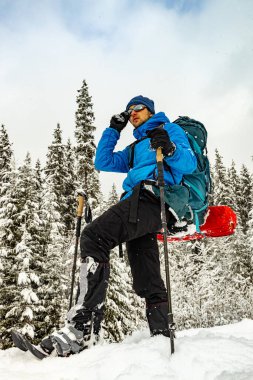 Sırt çantası ve kar ayakkabılarıyla dağlarda kış yürüyüşü..
