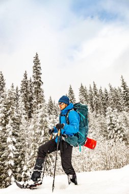 Sırt çantası ve kar ayakkabılarıyla dağlarda kış yürüyüşü..
