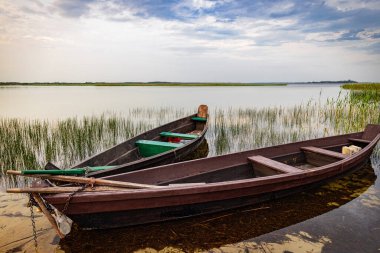 Kürekleri gölün kıyısında, güzel bir manzaranın arka planında olan tahta bir tekne..