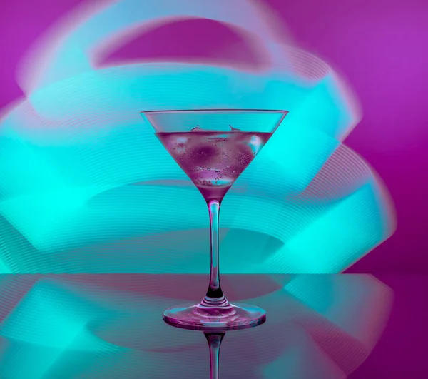 stock image Alcoholic cocktail in a glass goblet against the background of bright neon lights