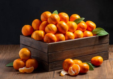 Tahta bir kutuda yeşil yapraklı bir grup mandalina. 