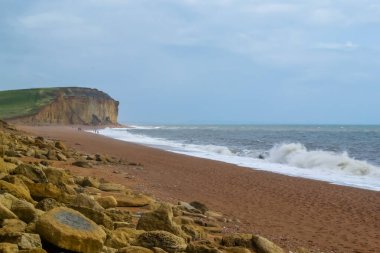 Büyük taşları olan bir sahil kenarında fırtınalı bir deniz
