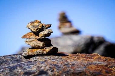 Düz gri taşlar bir piramit oluşturarak dağlardaki patikayı işaret ediyor.