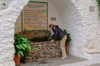 Genç ve sarışın kadın, tipik Granada Alpujarra kasabası Pampaneira 'nın çeşmesinde serinliyor.