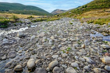 Sierra de Gredos 'taki El Mellizo sığınma bölgesindeki yuvarlak taşlarıyla Barbellido nehrinin panoramik manzarası.